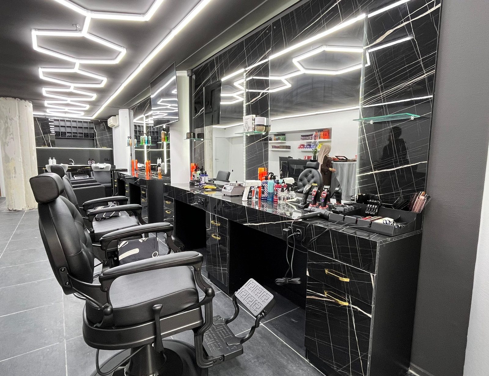 Rij kappersstations met spiegels, zwart marmer en zeshoekige ledlampen